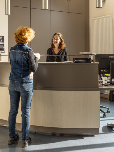 Photo de l'accueil de la mairie avec une personne qui demande des renseignements à l'agent d'accueil