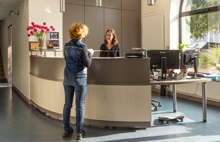 Photo de l'accueil de la mairie avec une personne qui demande des renseignements à l'agent d'accueil